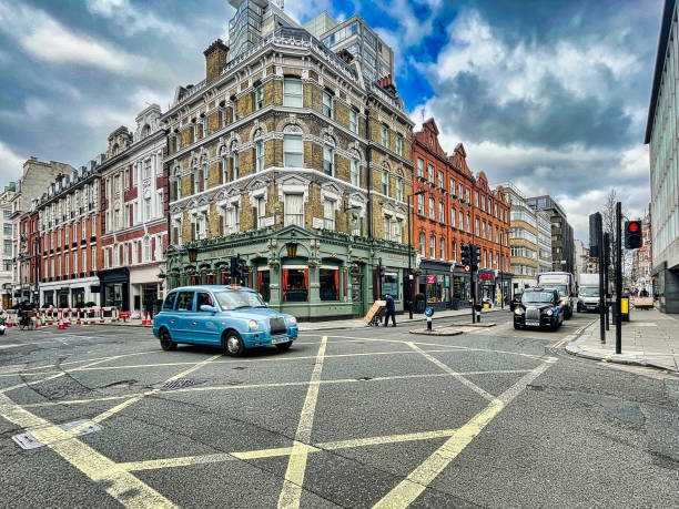 London, United Kingdom - March 07 2022: a taxi cab drives on a road and crosses an intersection with crosses painted on the asphalt