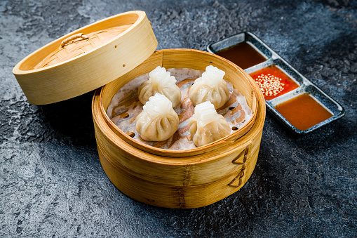 dim sum with pork with sauces on dark stone table