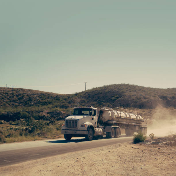 semi truck transporting chemicals/propane driving on a dirt road in new mexico, usa - oil industry industry new mexico oil drill imagens e fotografias de stock