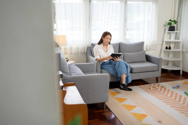 istock Young asian woman using tablet on sofa in living room 1432061488