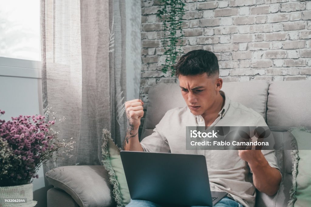 Man Using Computer To Watch Youtube Angry Young Man Using Computer Pc At Home Sitting On The Sofa Having ...