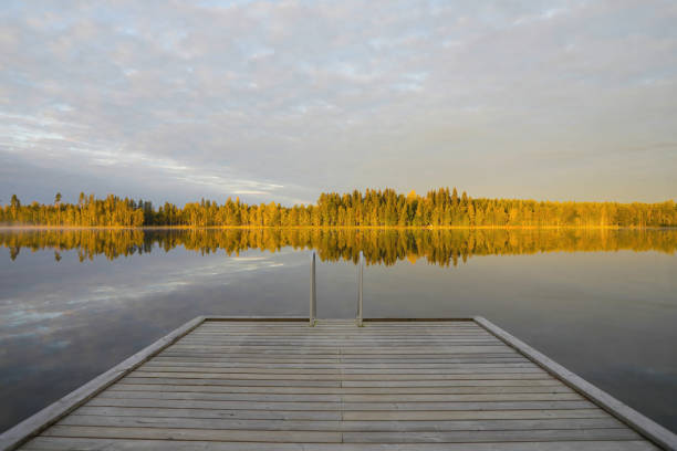 istock Dock on beautiful lake with fall foliage reflecting on the water 1432063368