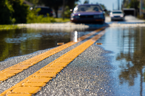A car creates a wake as it drives through a flooded road after a severe rain storm.