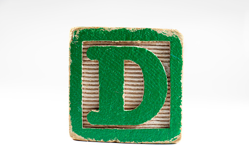 Retro vintage green and white toy block of the letter D. The block shows years of wear from play and learning