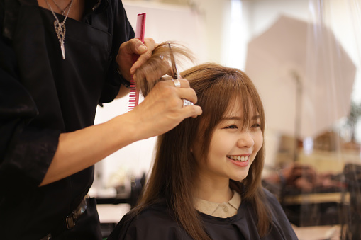 Male hairdresser cutting woman's hair