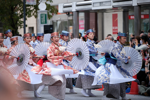 Ikebukuro, Tokyo / Japan - October 8 2022: Crowd of Yosakoi dancers wearing blue and red costumes performing in the streets during Tokyo Yosakoi festival.