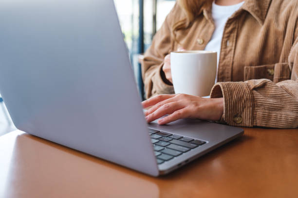 istock Closeup image of a woman using and working on laptop computer while drinking coffee 1432084409