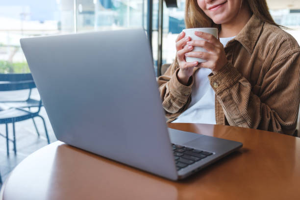 istock Closeup image of a woman using and working on laptop computer while drinking coffee 1432084954