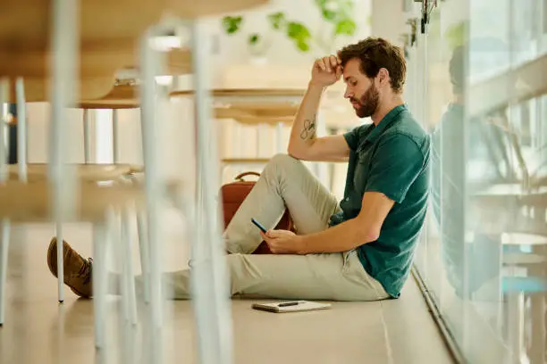 Photo of Depression, fail or anxiety university student on floor thinking of mistake, exam report stress, university debt or learning mistake. Sad, depressed and burnout college man with mental health problem