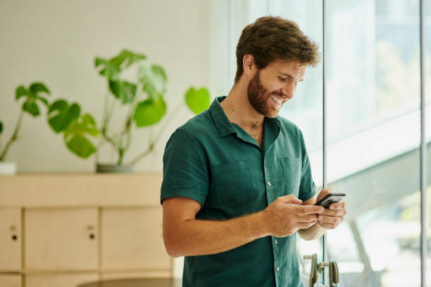 istock Smile, phone and 5g network connection while typing, messaging or chatting on social media looking happy while flirting online inside. German male using smartphone for communication or mobile app 1432095336