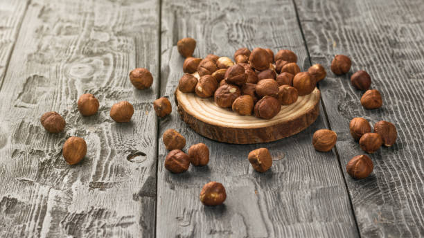 istock Hazelnuts scattered on a wooden stand on a wooden table. 1432096347