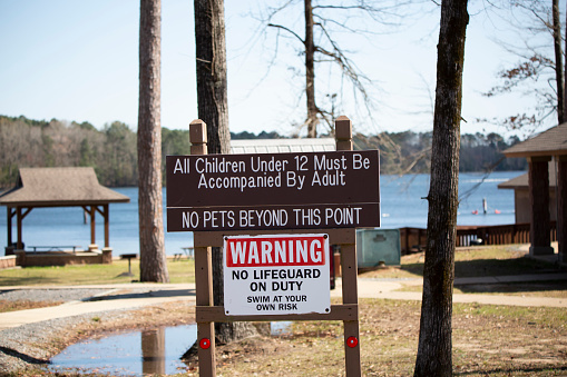 Jimmie Davis State Park, Louisiana, United States - March 18 2022: Sign warning that no lifeguard is on duty and all children under the age of 12 have to be accompanied by an adult
