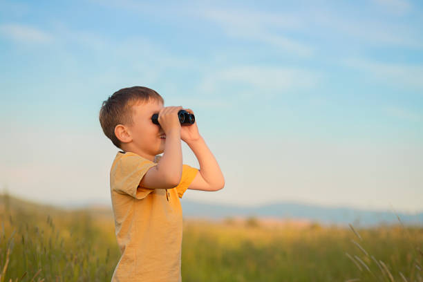 istock a boy stands in a field and looks through binoculars 1432098263