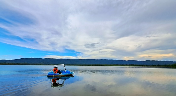 Adult couple driving padle boat on lake.