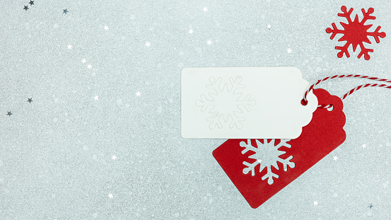 gift tags with snowflakes on silver background with star confetti. flat lay, top view. christmas greeting card.