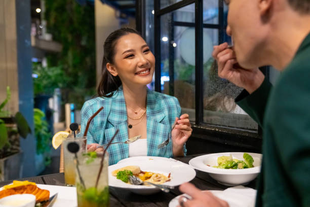 casal asiático celebrando e jantando no restaurante da cidade à noite. - thailand restaurant cocktail bar - fotografias e filmes do acervo