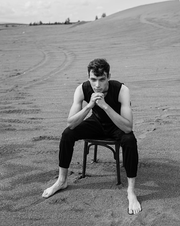 Lone Man sitting on chair in desert. black and white