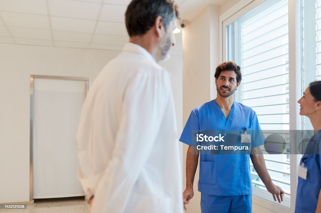 Male Nurse Sharing A Funny Story With A Doctor And Another Nurse In The  Hospital Corridor Stock Photo - Download Image Now - iStock