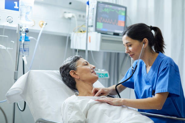 Nurse carefully listening to patient's heart rate in hospital. stock photo
