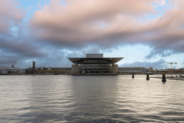 The Copenhagen Opera House, or Operaen stands across the harbor, framed by calm blue water and a clear sky on a bright winter day.