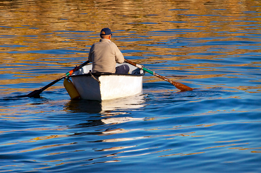 Finisterre, A Coruña, Spain - January 18, 2022: Finisterre harbor, costa da morte, A Coruña province, Galicia, Spain. Rear view of senior fisherman rowing .