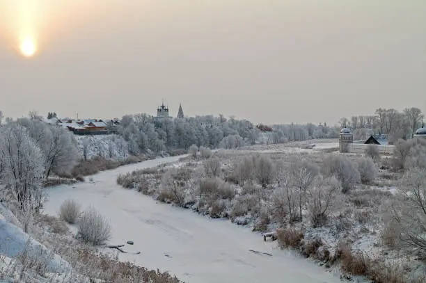 View of Suzdal from the high bank of the Kamenka River. The sun breaks through the clouds. December.