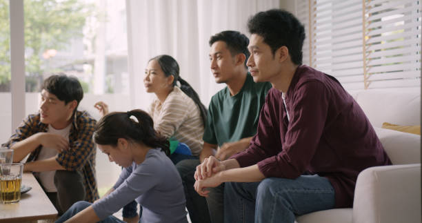 若い大人の友人の男性と女性のグループのアジアの人々は、自宅でテレビでゲームを見てソファに座って - ワールドカップ　日本人 ストックフォトと画像