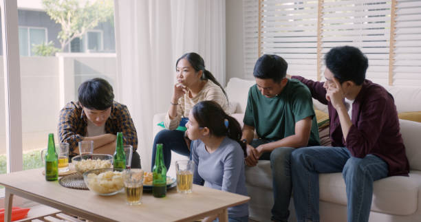 若い大人の友人の男性と女性のグループのアジアの人々は、自宅でテレビでゲームを見てソファに座って - ワールドカップ　日本人 ストックフォトと画像