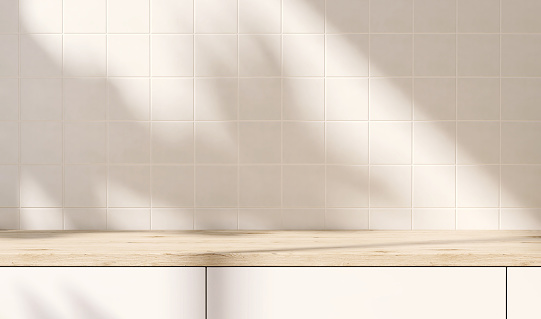 Encimera de cocina incorporada moderna y de lujo con encimera de madera, gabinete a la luz del sol y sombra de hoja desde la ventana en la pared de azulejos de color crema photo