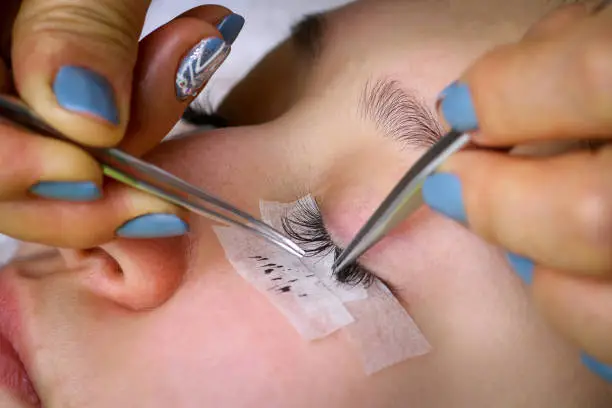 Photo of Eyelash extension procedure, woman eye with Long eyelashes