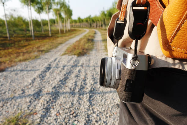 man carrying a camera walking on the dirt road