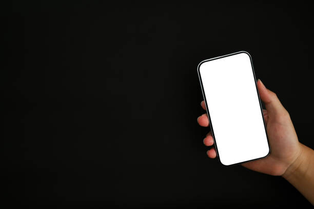 istock Close up view of hand holding mock up smart phone with empty screen isolated on black background. 1432135276
