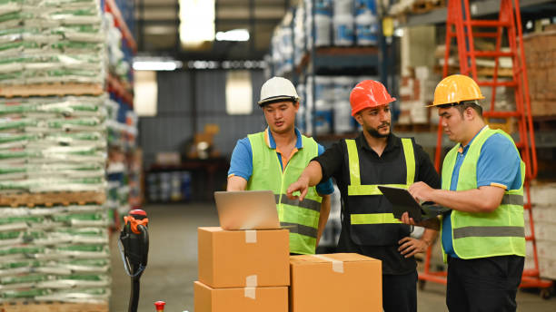 istock Image of warehouse workers are inspecting stock on laptop while standing aisle between rows of tall shelves full of packed boxes. 1432135334