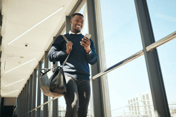 homem de negócios de viagens recebendo e-mail ou notificação de mídia social enquanto caminhava para o trabalho em empresa corporativa. feliz profissional lendo um boletim informativo de desconto de marketing para o voo da classe executiva do aeroporto - viagem de negócios - fotografias e filmes do acervo