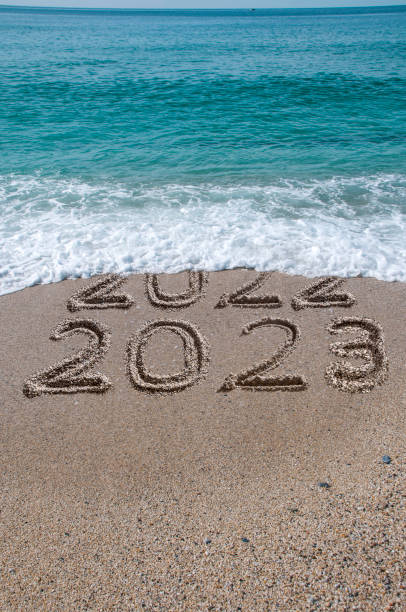 Welcome 2023 New year 2023 written on sandy beach with waves 2023 2022 stock pictures, royalty-free photos & images