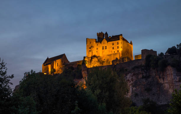 the illuminated castle of Beynac in the evening in the Dordogne area in France The illuminated Chateau de Beynac towers in the evening over the town of Beynac which clings to the rocks in a bend of the Dordogne river, France hystoric stock pictures, royalty-free photos & images