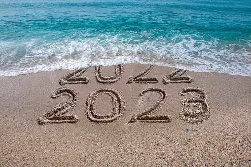 New year 2023 written on sandy beach with waves