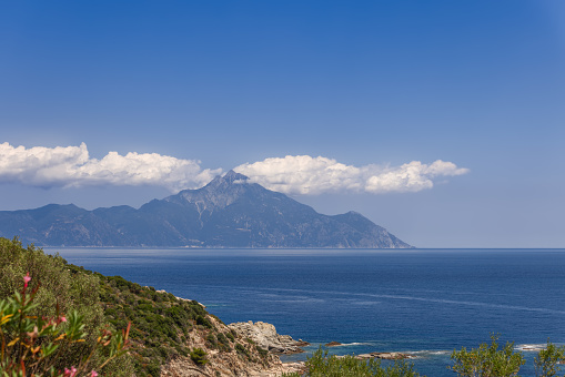 White cumulus clouds gathered together around the top of Mount Athos on a summer afternoon. Photo was taken from opposite coast of the Singitic Gulf of the Sithonia Peninsula, Greece