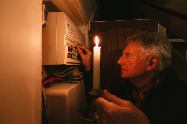 istock Senior man checking home fuse box by candlelight during power outage 1432151878