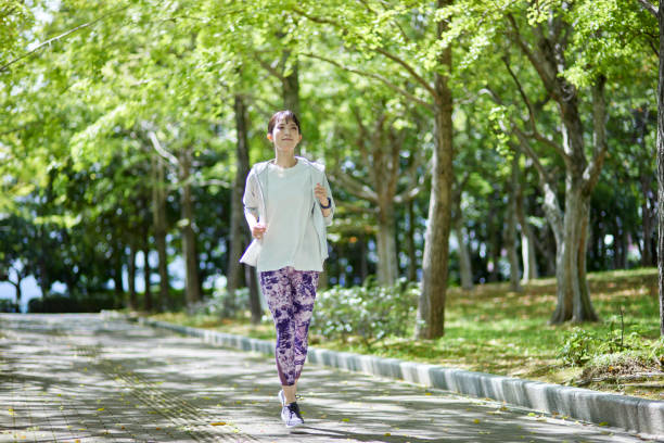 giovane donna giapponese che esercita nel parco - gara di marcia veloce foto e immagini stock