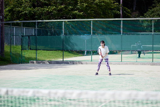 Young Japanese woman playing tennis on the tennis court