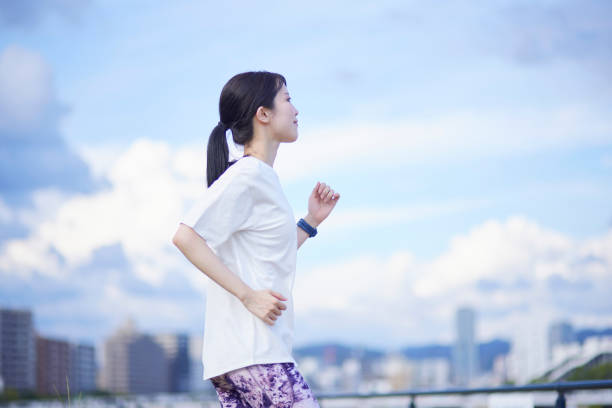 屋外で運動する若い日本人女性 - walking towards ストックフォトと画像