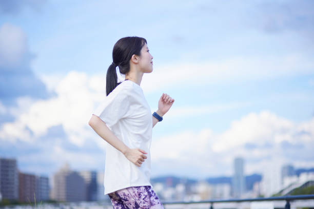 young japanese woman exercising outdoors - snelwandelen stockfoto's en -beelden