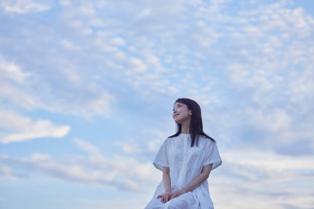 夕暮れ時の青空と白いドレスを着た女性 - 自信 ストックフォトと画像