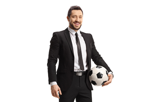 Businessman in a suit holding a soccer ball and looking at the camera isolated on white background