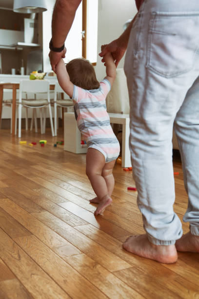 отец учит своего мальчика ходить - babies and children cheerful low angle view vertical стоковые фото и изображения