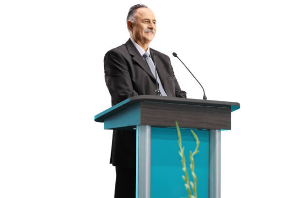 mature businessman giving a speech on a podium and smiling - podium lectern microphone white imagens e fotografias de stock