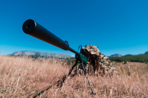 army soldier holding sniper rifle with scope and aiming in forest. war, army, technology and people concept. High quality photo