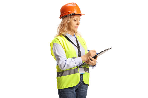 istock Female engineer with a safety vest and helmet writing a document 1432158307