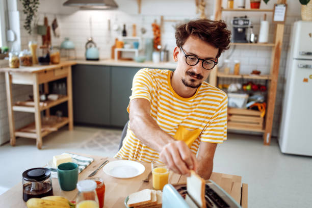 istock Young casually clothed man making breakfast in his apartment 1432158709